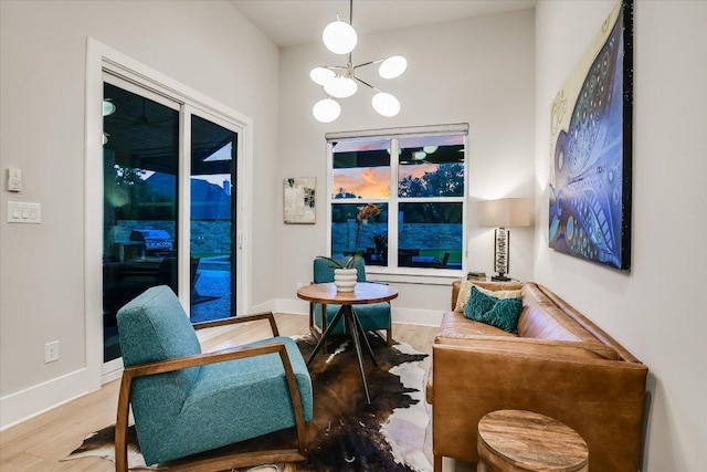 living area with baseboards, wood finished floors, and a chandelier
