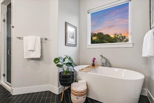 full bathroom with baseboards, a freestanding bath, and a stall shower