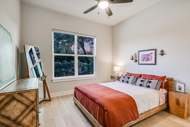 bedroom featuring baseboards, multiple windows, a ceiling fan, and light wood-style flooring
