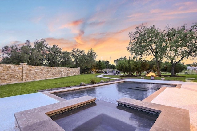 view of swimming pool featuring a lawn, a pool with connected hot tub, and fence