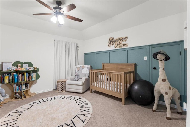 bedroom featuring a ceiling fan, light colored carpet, a crib, and vaulted ceiling