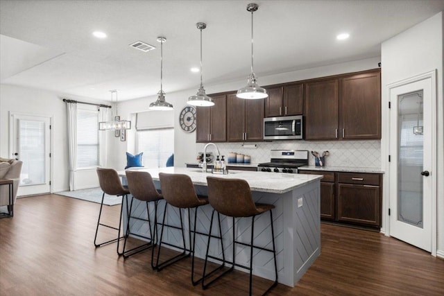 kitchen with a sink, tasteful backsplash, stainless steel appliances, and dark wood-style floors