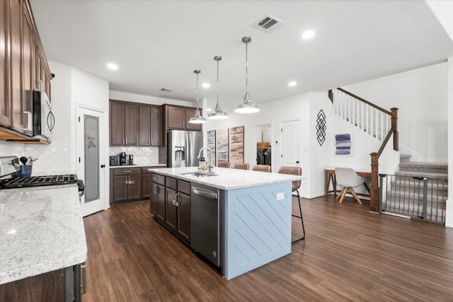 kitchen with a breakfast bar, dark wood-type flooring, tasteful backsplash, a sink, and stainless steel appliances