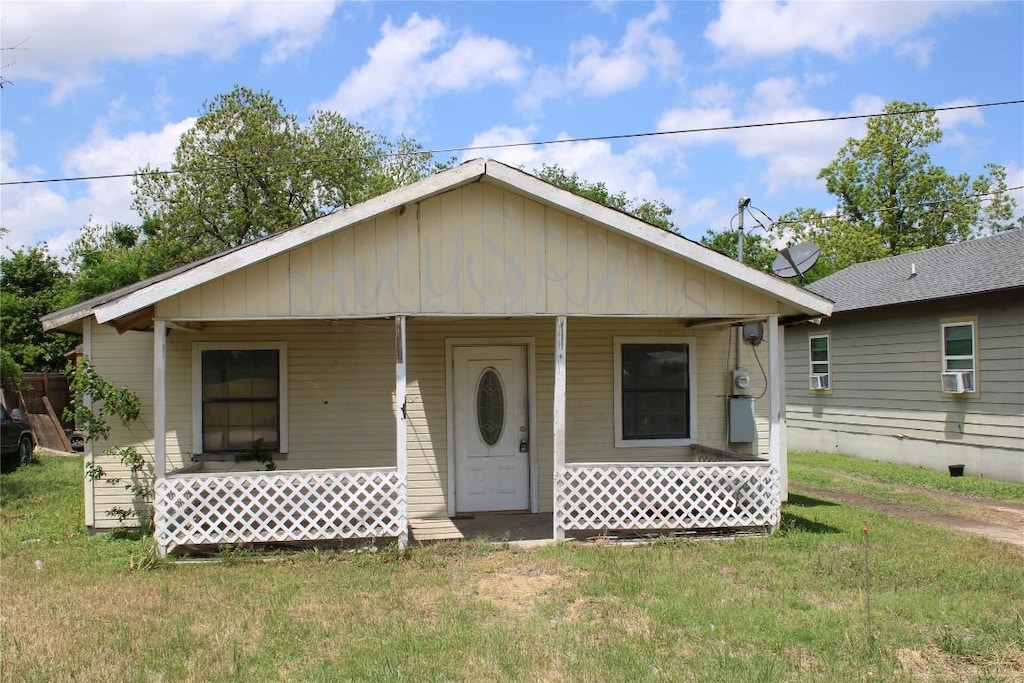 bungalow-style house with a porch, cooling unit, and a front yard