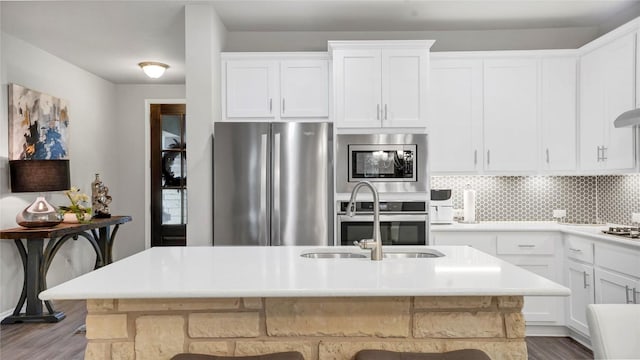 kitchen with decorative backsplash, appliances with stainless steel finishes, wood finished floors, and white cabinets