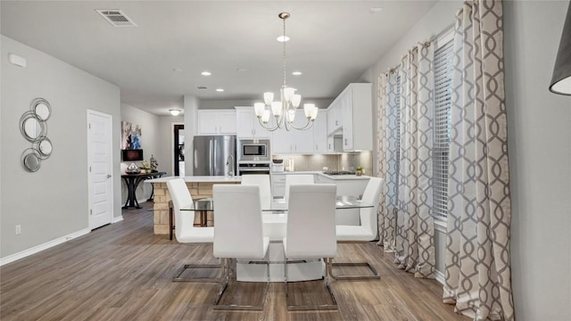 dining room with visible vents, wood finished floors, baseboards, recessed lighting, and a notable chandelier