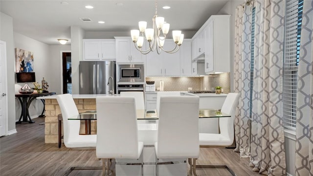 1621 Winding Stream Trl, Leander, TX 78641 - kitchen featuring stainless steel appliances, a chandelier, wood finished floors, decorative backsplash, and an island with sink
