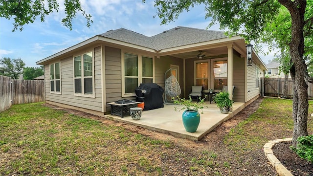back of property with a shingled roof, ceiling fan, a fenced backyard, a patio area, and a yard