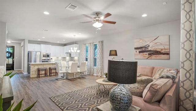 living room with recessed lighting, visible vents, light wood finished floors, and ceiling fan with notable chandelier
