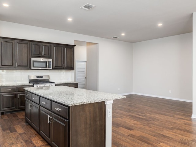 kitchen featuring a center island, baseboards, dark wood-style floors, stainless steel appliances, and recessed lighting