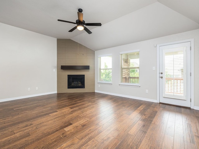 unfurnished living room featuring dark wood-style flooring, lofted ceiling, a fireplace, baseboards, and a ceiling fan