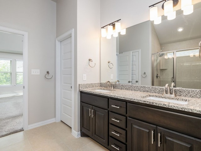 full bathroom with double vanity, a sink, baseboards, and a stall shower