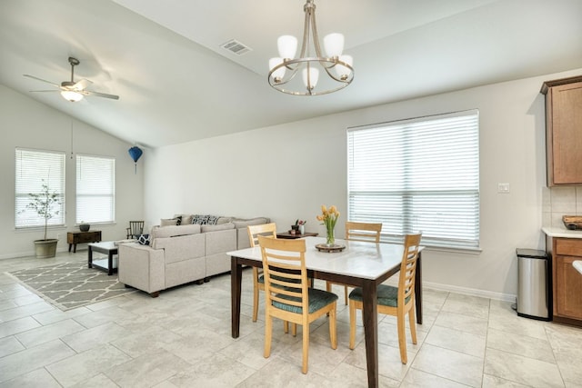 dining room with ceiling fan with notable chandelier, baseboards, light tile patterned floors, vaulted ceiling, and visible vents