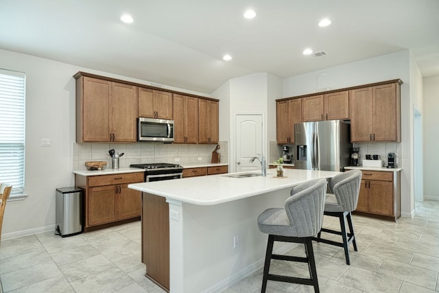 kitchen featuring baseboards, a breakfast bar area, a sink, appliances with stainless steel finishes, and backsplash