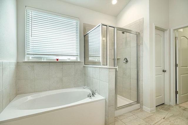 full bathroom featuring a bath and a shower stall