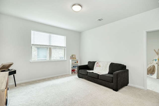 living area featuring baseboards, visible vents, and light colored carpet