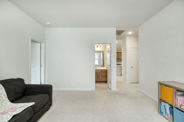 sitting room with baseboards and light colored carpet