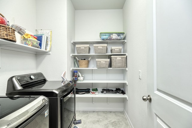 clothes washing area featuring laundry area, baseboards, and washer and dryer