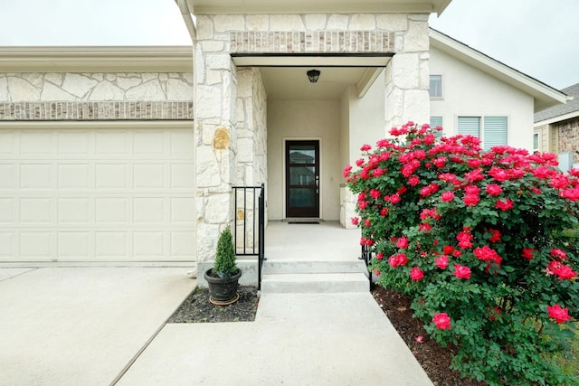 532 Tanda Ln, Hutto, TX 78634 - view of exterior entry featuring stone siding, a garage, stucco siding, and concrete driveway