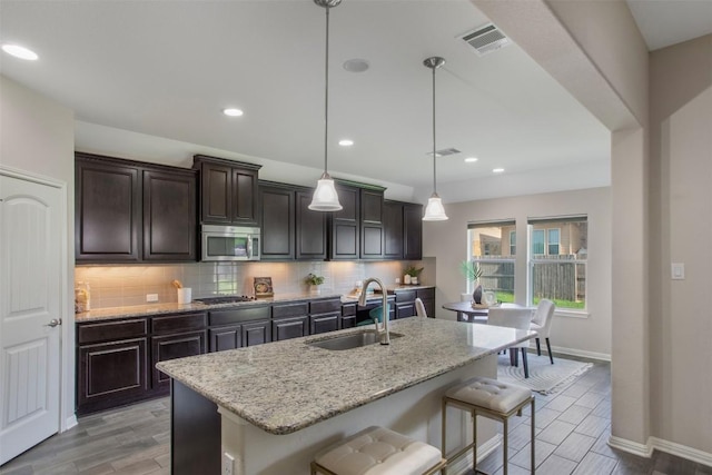 108 Poppy Ct, Georgetown, TX 78626 - kitchen featuring appliances with stainless steel finishes, a breakfast bar, a sink, baseboards, and tasteful backsplash