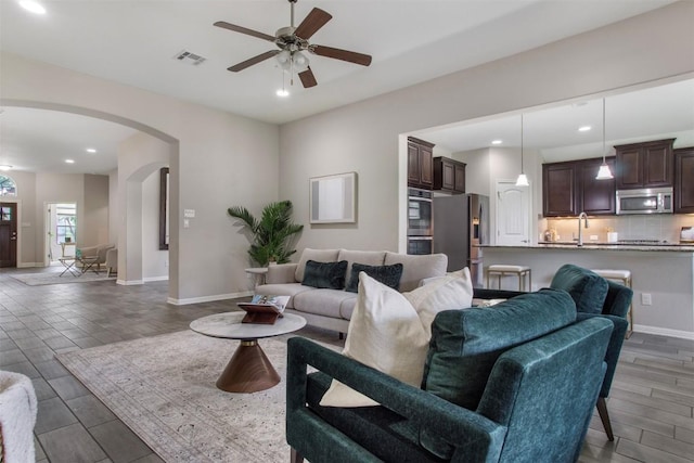 living room featuring ceiling fan, wood finish floors, arched walkways, recessed lighting, and visible vents