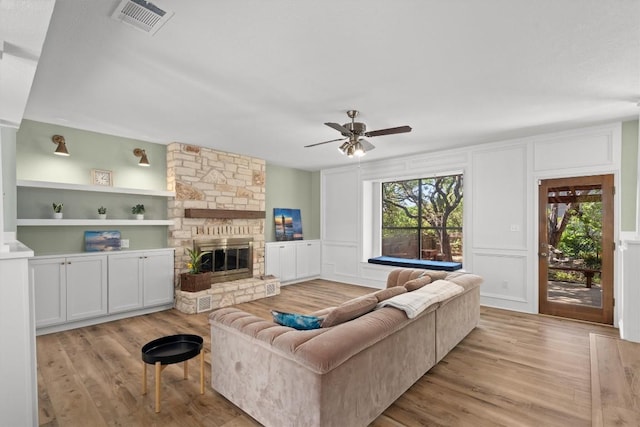 9800 Knotty Pine Cv, Austin, TX 78750 - living area featuring visible vents, light wood-style floors, a decorative wall, and a stone fireplace