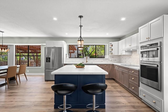 9800 Knotty Pine Cv, Austin, TX 78750 - kitchen with a kitchen island, appliances with stainless steel finishes, open shelves, a sink, and under cabinet range hood