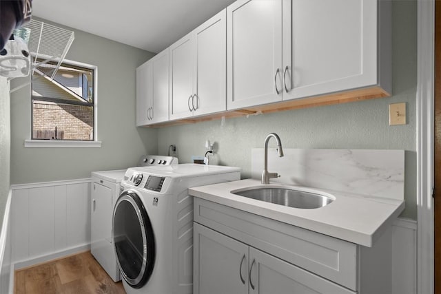 9800 Knotty Pine Cv, Austin, TX 78750 - laundry room with wainscoting, light wood-type flooring, cabinet space, a sink, and separate washer and dryer