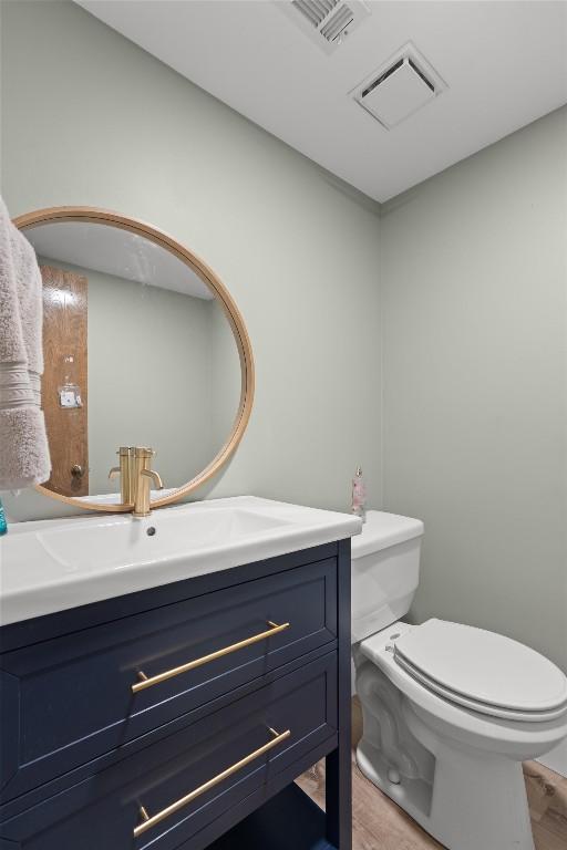 9800 Knotty Pine Cv, Austin, TX 78750 - half bathroom with toilet, visible vents, wood finished floors, and vanity