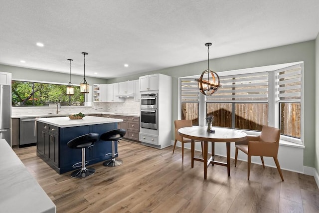 9800 Knotty Pine Cv, Austin, TX 78750 - kitchen featuring appliances with stainless steel finishes, an inviting chandelier, light countertops, a center island, and decorative backsplash