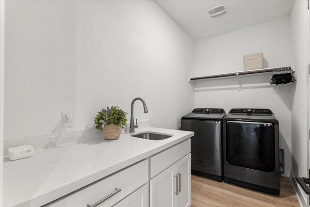 8401 Hubble Walk, Austin, TX 78744 - laundry room featuring independent washer and dryer, light wood-style flooring, and cabinet space