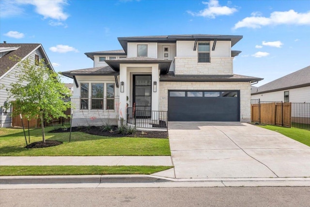 prairie-style home featuring a garage, fence, a front yard, stone siding, and driveway