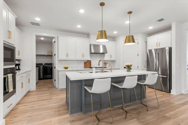 kitchen featuring independent washer and dryer, visible vents, light countertops, freestanding refrigerator, and under cabinet range hood
