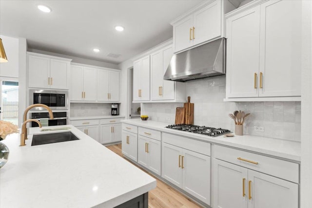 kitchen featuring light countertops, under cabinet range hood, white cabinets, a sink, and appliances with stainless steel finishes