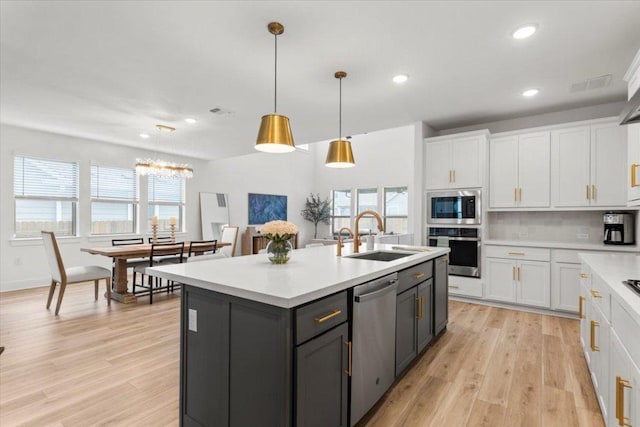 kitchen with light countertops, white cabinets, tasteful backsplash, a sink, and appliances with stainless steel finishes