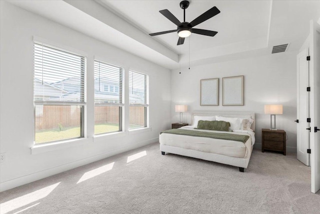 bedroom with ceiling fan, carpet, a tray ceiling, and visible vents