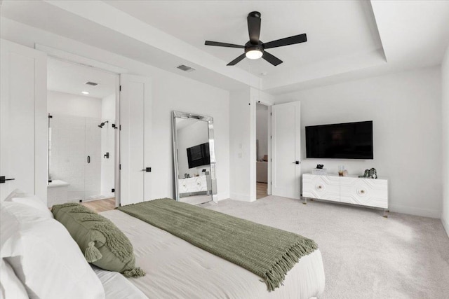 bedroom featuring visible vents, a raised ceiling, baseboards, and light colored carpet