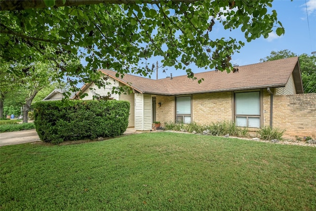 ranch-style home with brick siding, fence, and a front lawn