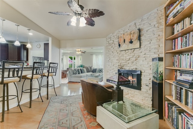 living room with light wood-style floors, a ceiling fan, and a fireplace