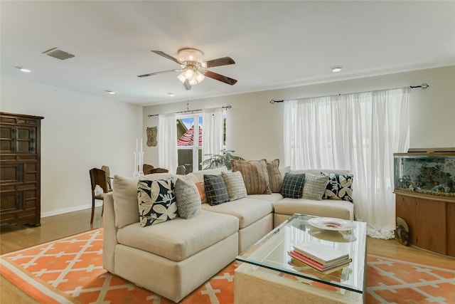 living room with baseboards, ceiling fan, visible vents, and wood finished floors