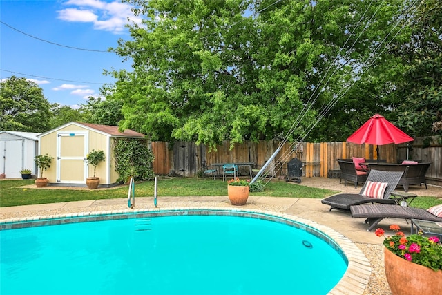 view of swimming pool with an outdoor structure, a fenced backyard, a shed, a fenced in pool, and a patio area