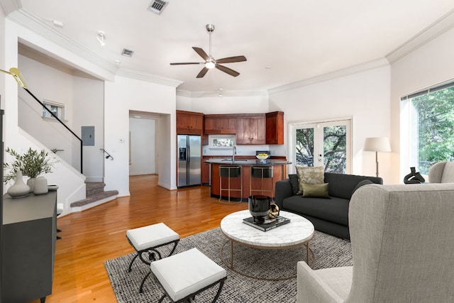 5310 Scenic View Dr, Austin, TX 78746 - living room featuring stairs, ceiling fan, light wood-type flooring, crown molding, and french doors