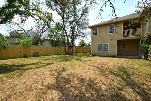 view of yard with a fenced backyard and a balcony