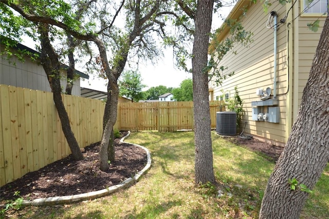 view of yard featuring central AC and fence