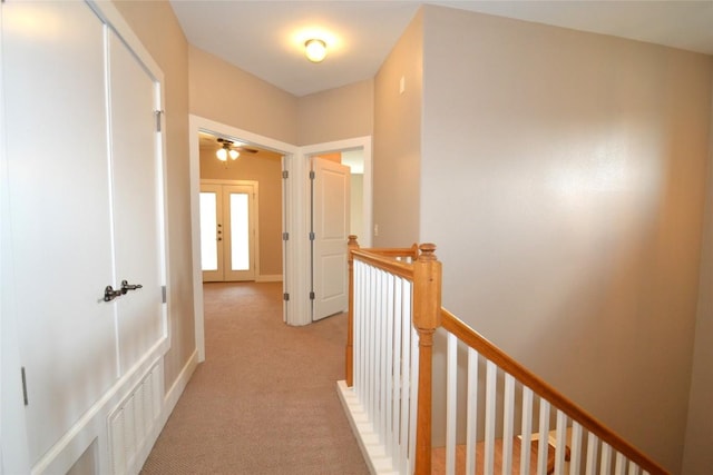 corridor with french doors, light carpet, an upstairs landing, and visible vents