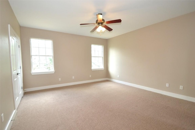 empty room with baseboards, a wealth of natural light, ceiling fan, and light colored carpet