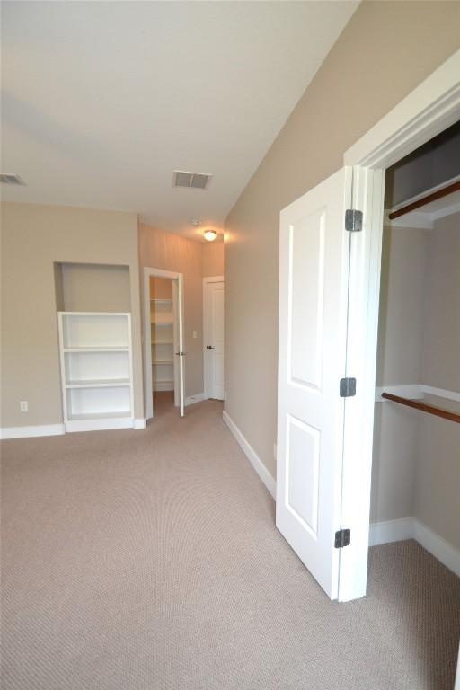 unfurnished bedroom featuring visible vents, baseboards, a closet, and light carpet