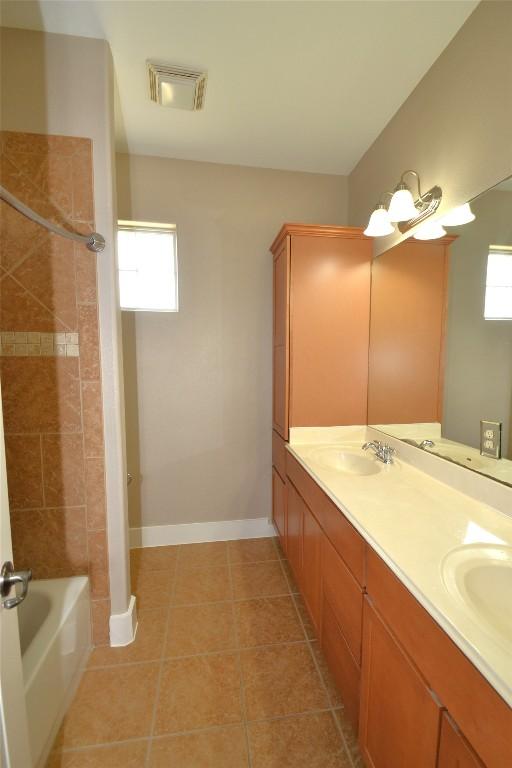 full bathroom featuring double vanity, visible vents, shower / tub combination, a sink, and tile patterned floors