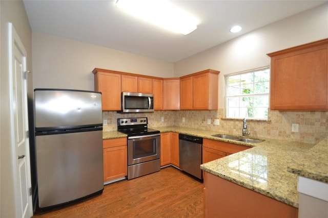 kitchen with light wood-type flooring, a sink, decorative backsplash, and stainless steel appliances