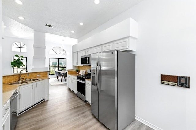 7419 Dallas Dr, Austin, TX 78729 - kitchen featuring stainless steel appliances, a sink, white cabinets, backsplash, and recessed lighting